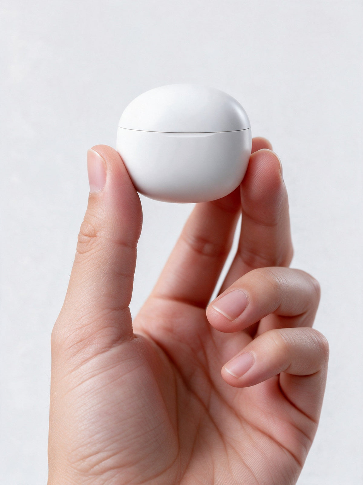 Sleepsono charging case held between thumb and fingers to show how small it is